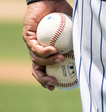 hand holding two baseball balls